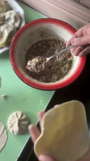 Порашивание фарша в миске и наполнение тестовой заготовки: видно ложку с мясной начинкой и подготовленную оболочку для лепки хинкали.