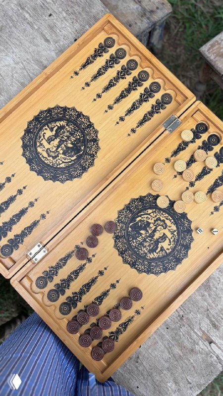 Деревянные нарды с тёмными и светлыми фишками на столе — домашняя настольная игра как часть деревенского досуга и общения.