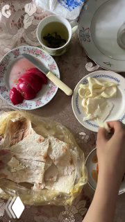 Столовая сцена: лаваш, нарезанный сыр, чашка травяного чая и руки за столом — деревенский завтрак или лёгкий перекус в семейной обстановке.