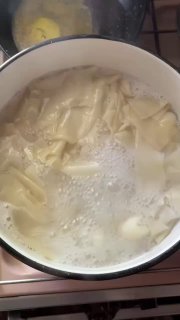 Варящиеся кусочки теста в кастрюле, вид процесса приготовления — плавающие вареники в кипящей воде.