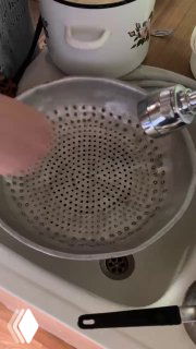 Дуршлаг и металлическая миска на кухонной поверхности — подготовка к отцеживанию отваренного теста, бытовая посуда и руки в кадре.