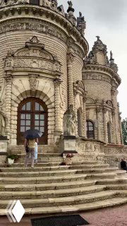 Крупный план жерла и входной части Знаменской церкви: арочные окна, ступени и люди с зонтами на фоне каменной отделки.