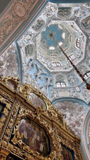 Интерьер Знаменской церкви: декоративный резной иконостас и расписной свод с росписями в пастельных тонах, вид снизу вверх.