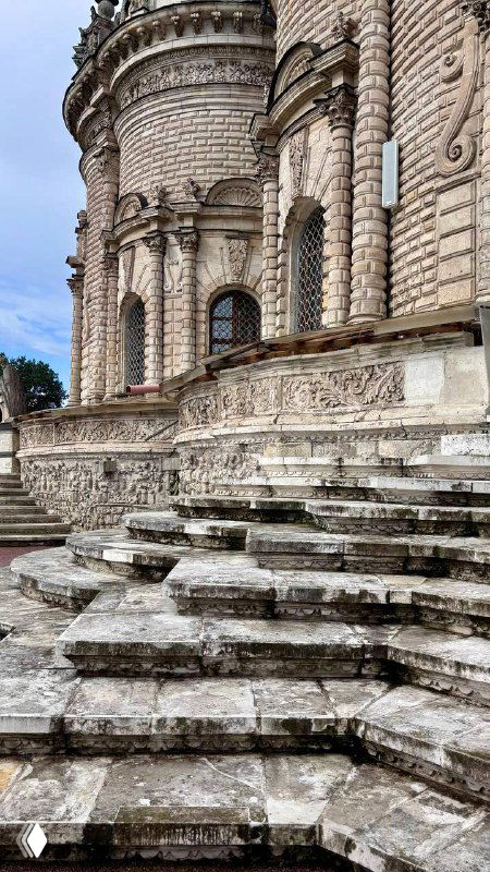 Боковой фасад Знаменской церкви с арочными окнами и массивными ступенями, видно фактуру старинного камня и архитектурные рельефы.