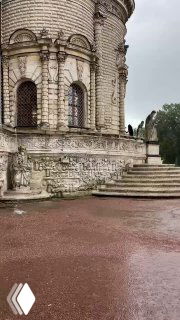 Фрагмент наружной стены усадебного храма с барельефами и потертостями камня, акцент на изящной скульптурной отделке.