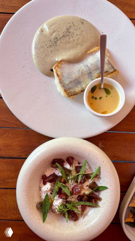 Белая тарелка со страчетеллой или нежной закуской и маленькой чашкой с соусом; кадр подчёркивает текстуру блюда и минималистичную подачу.