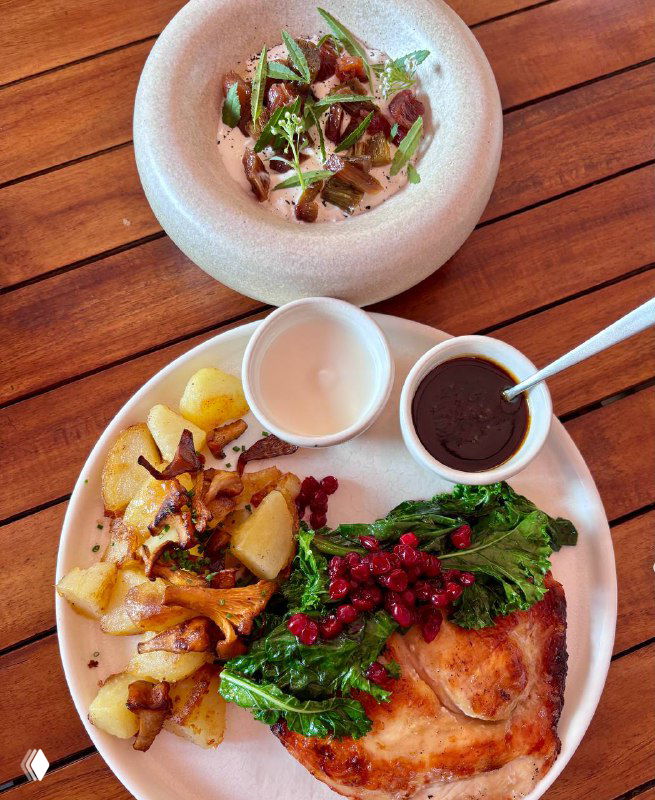 Тарелка с деликатным холодным блюдом, зелёными листочками и мелкими компонентами — аккуратная современная подача на светлой посуде.