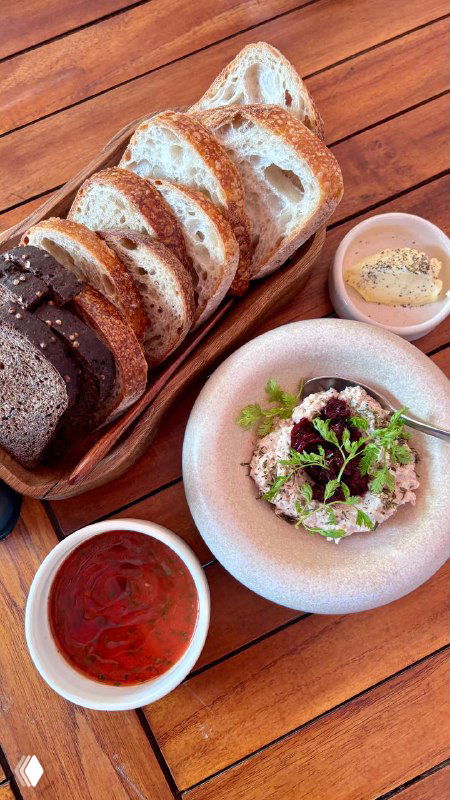 Большая тарелка с порцией: запечённая птица, картофель, зелень и две соусницы — вид сверху на насыщенную и колоритную композицию блюда.