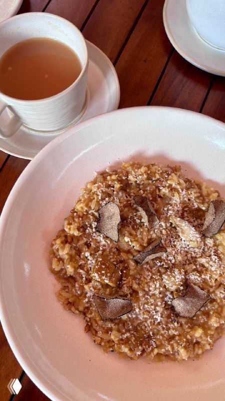 Хлебная тарелка и мисочка с закуской на деревянном столе; рядом чашки и соусы — уютный элемент сервировки перед основными блюдами.