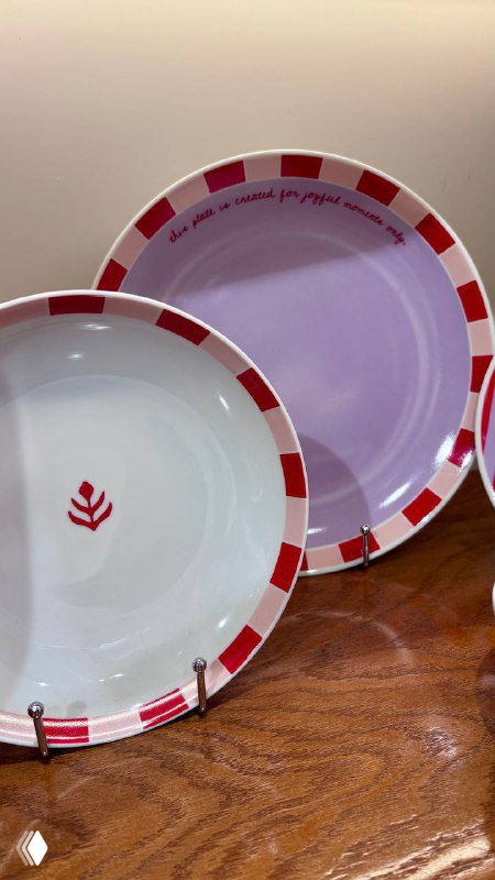 Крупный план декоративных тарелок пастельных тонов на полке в магазине-корнере Nuself: узоры, форма и цвет в фокусе, предметы декора для дома.