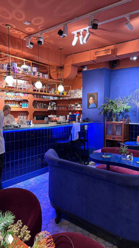 Барная зона и мягкие диваны в тёплых пастельных тонах — интерьер в стиле кинематографа и Уеса Андерсона в кафе Скворец