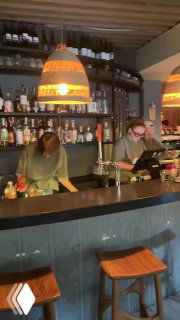 Барная зона Tacobar: бармены за стойкой, полки с бутылками и приглушённый свет — атмосферный вид заведения в центре Москвы