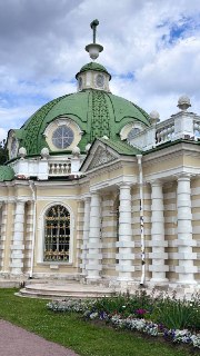 Фасад ротонды усадьбы с зелёной купольной крышей, арочными окнами и цветочной клумбой у основания, вид с зелёной лужайки на фотографии из фотозаметок.