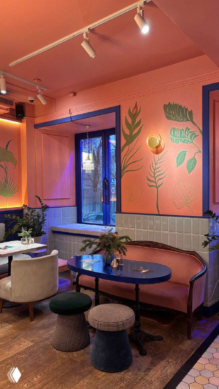 Розово-голубой интерьер кафе с картинами на стенах, столиками и пуфами — атмосфера в духе режиссера Уеса Андерсона в Скворце