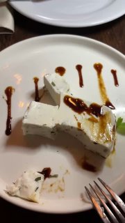 Кусок армянского белого сыра на тарелке с тёмным соусом и следами приборов — минималистичная закуска в ресторане.