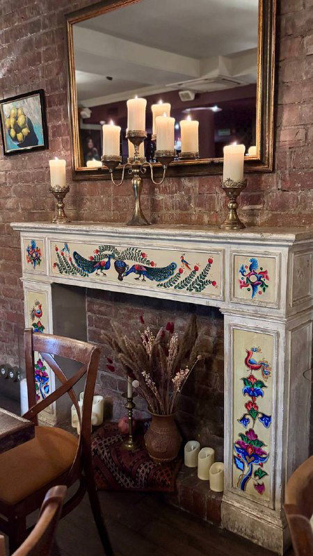Интерьер ресторана с камином и декоративной плиткой, свечами и уютными креслами — атмосфера домашнего армянского заведения.