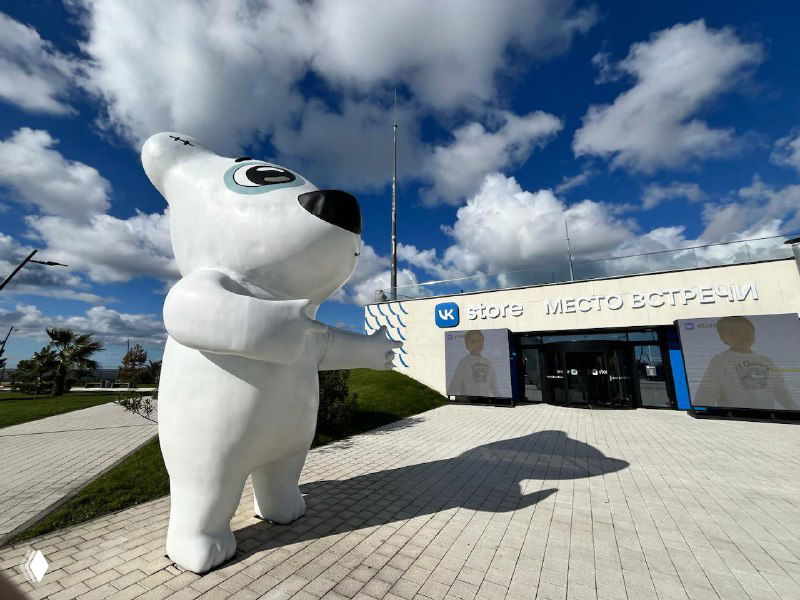 Большая белая фигура талисмана у входа VK.DOM: массивная скульптура на открытой площадке перед зданием и современная внешняя архитектура комплекса.