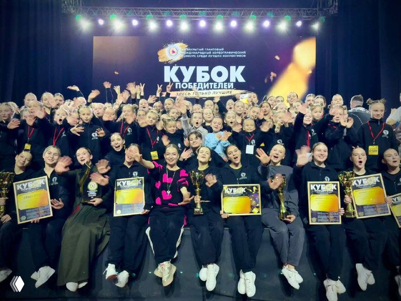 Групповая фотография рязанского коллектива «20.13» на сцене в Сочи: танцоры с кубками, дипломами и баннером «Кубок Победителей», поздравления и награды.