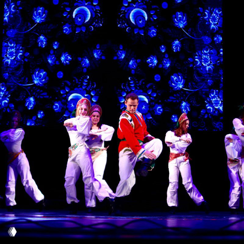 Массовый танцевальный номер с артистами в сценических костюмах на фоне эффектного видеоряда, сценическая хореография и синхронные движения.