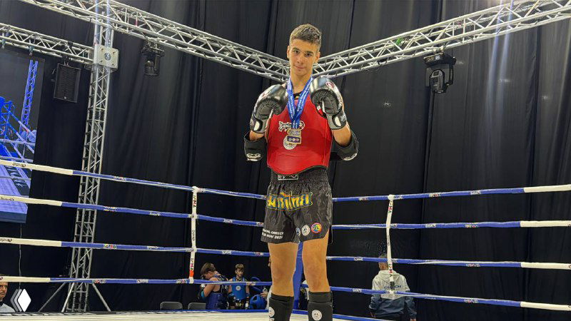 Артём Хохлов в ринге после победы, в экипировке муайтай с медалью на шее; кадр с финала Первенства Европы в Афинах.