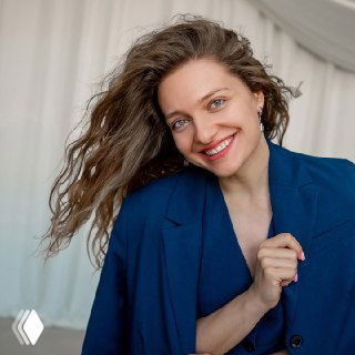 Улыбающаяся женщина в синем пиджаке на светлом фоне, портретный снимок с сайта «Центральная школа», иллюстрация материала о премии «Знание».