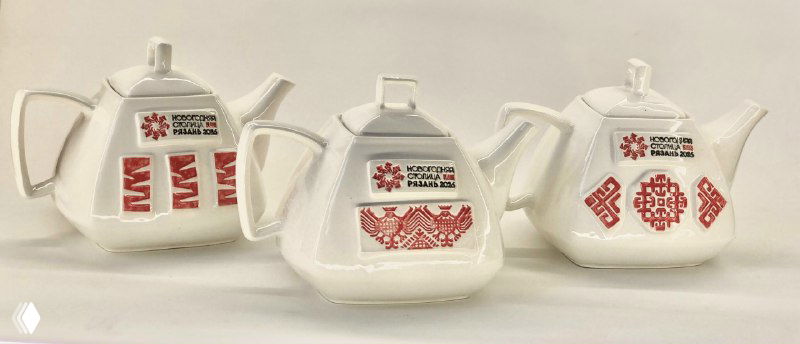 Три чайника из белой скопинской керамики с красным орнаментом и логотипом Новогодней столицы России — 2026 в крупном плане