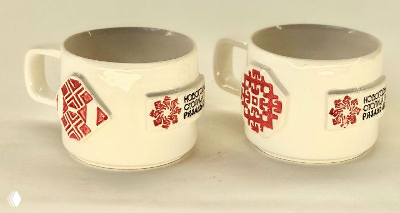 Чайные чашки и бокалы с ручками, украшенные традиционным красным орнаментом и маркировкой «Новогодняя столица Рязань 2026» вблизи