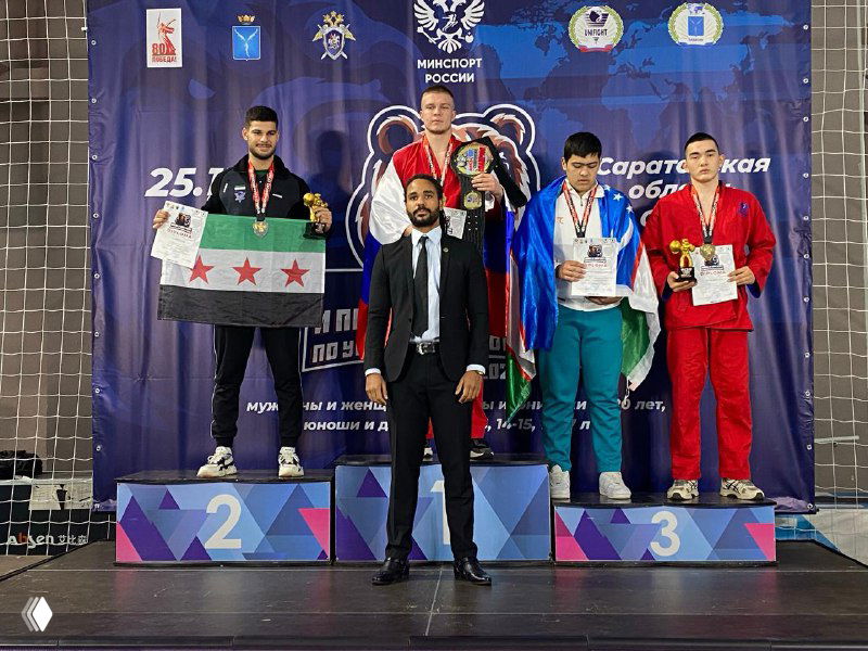 Победители на пьедестале чемпионата по универсальному бою: четверо бойцов с медалями и дипломами на фоне официального баннера турнира.