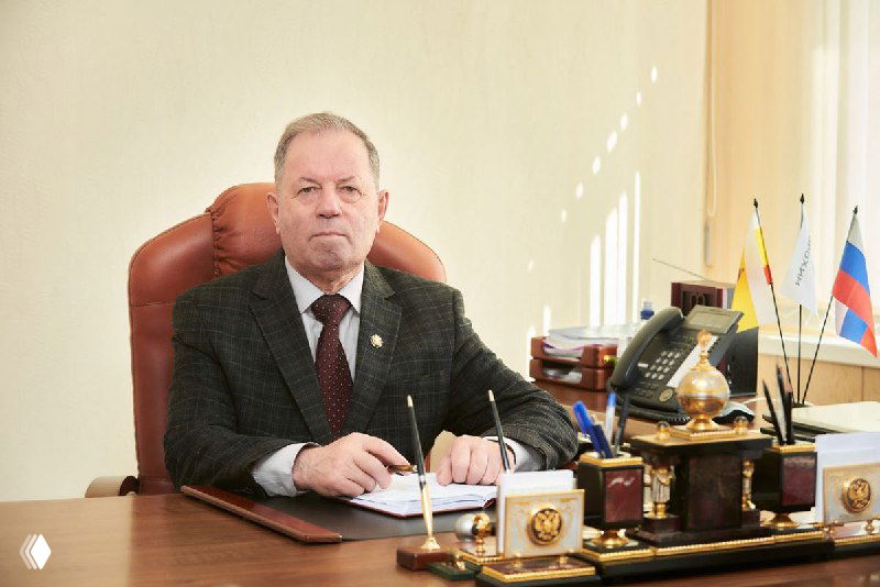 Владимир Бродский за рабочим столом в кабинете: портрет руководителя ОАО «Рязаньагрохим», флаги и документы на столе