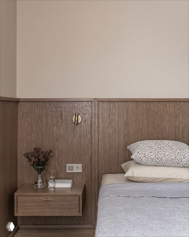 Ближний план прикроватной зоны: изящная деревянная панель, плавающая тумбочка, книги и ваза с сухоцветами — детали, добавляющие уют и текстуру интерьеру.