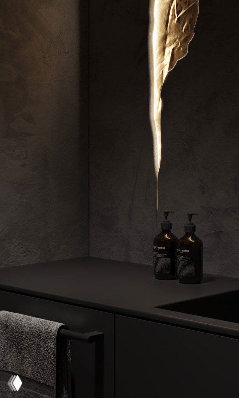 Крупный план чёрной столешницы и раковины в графитовом санузле с фактурной тёмной стеной, бутылочками и вертикальным светящимся элементом-«трещиной».