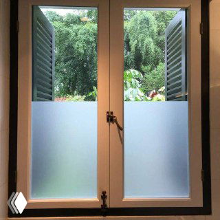 Окно с матовой пленкой на нижней части стекла, деревянная рама, вид на зелёный сад — пример приватного оформления окон без штор.