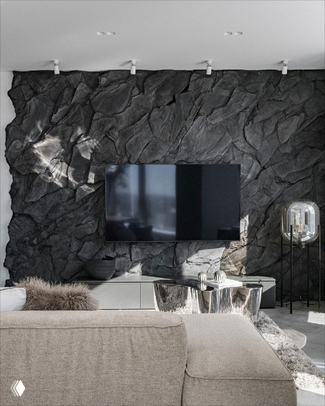 Рельефное панно под натуральный камень тёмно-серого тона за телевизором; видна текстура камней и контраст с мягкой мебелью в гостиной.