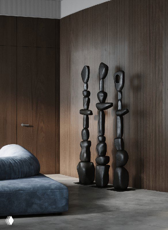 Полукруглая рейковая стена и три высокие абстрактные скульптуры‑тотемы тёмного тона, расположенные как арт-объекты на фоне древесных панелей интерьера.