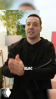 Человек в интерьере на фоне лампы и растения; кадр из ролика о проекте «Культура тела», обсуждение экономии на отделке стен.