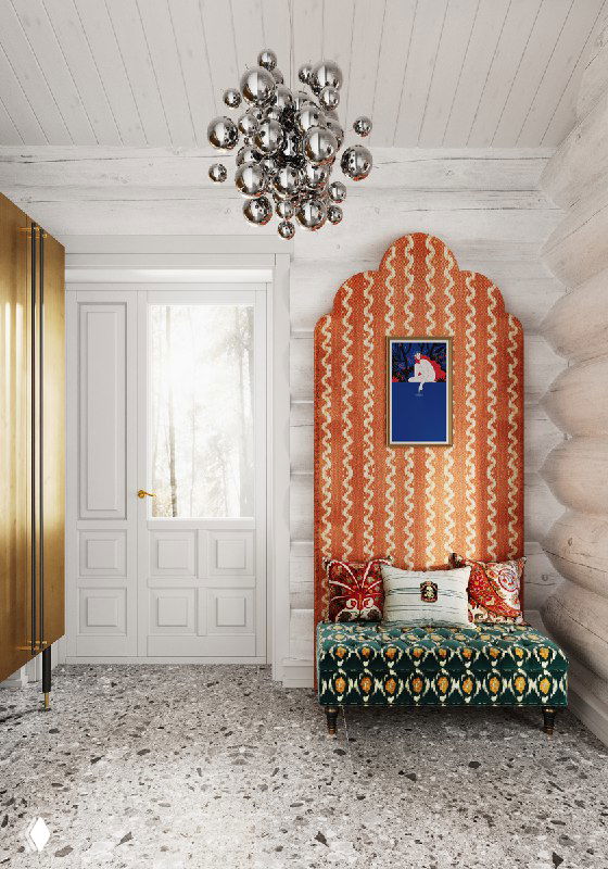 Визуал прихожей в доме из бревна: золотой шкаф слева, арочный яркий текстильный фон с кушеткой, металлическая люстра, белые бревенчатые стены, терраццо пол.
