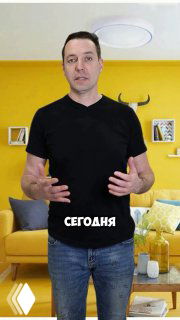 Мужчина в чёрной футболке на фоне яркой жёлтой гостиной с диваном и полками — иллюстрация влияния цвета в интерьере.