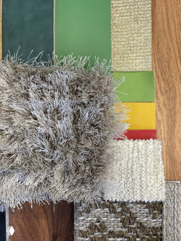 Подборка образцов материалов и текстур: ворсистый ковёр, образцы зелёных и горчичных тканей и природных фактур для оформления диванной и столовой зон проекта.