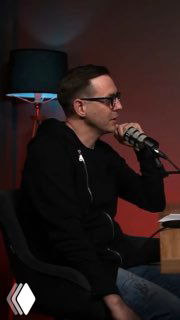 Иван Безруков в студии подкаста сидит у микрофона и рассказывает о демонтаже стен и ремонте квартиры; тёмный фон.