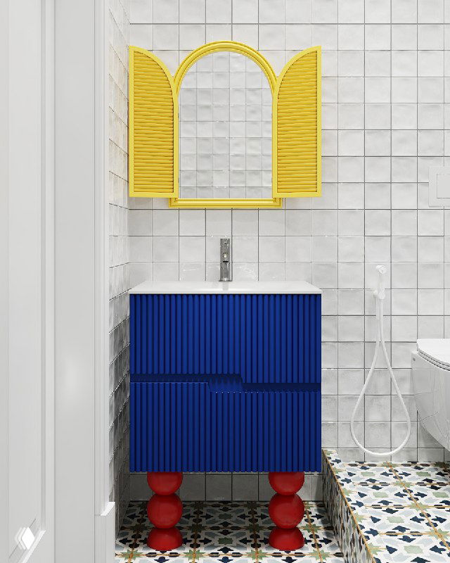 Крупный план санузла: синяя тумба на фигурных красных ножках, жёлое зеркало-ставни на фоне белой мелкоформатной плитки и орнаментного пола.