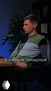 Гость подкаста в профиль: мужчина в свитере сидит у микрофона в студии; на кадре видна надпись «В НАЧАЛЕ ПРОШЛОЙ».