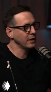 Мужчина в студии подкаста с микрофоном и очками; кадр показывает гостя разговора о ремонте и дизайне интерьера, близкий план