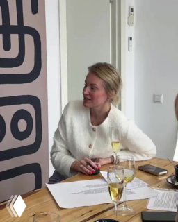 Фотография Ксении — студентки курса 'Магия дизайна', обсуждающей проект за столом с материалами и документами во время презентации.