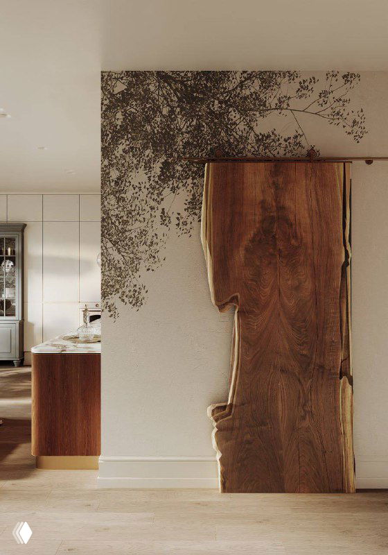 Дверь в гардеробную из цельного спила дерева на фоне стены с фреской ветвистого дерева и натуральными текстурами интерьера.