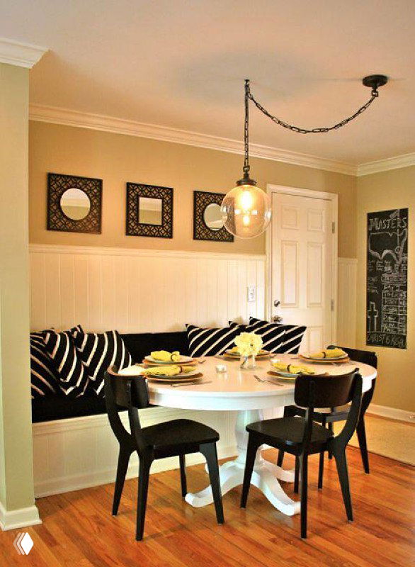 Небольшая столовая с круглым столом и ретро-лампой на цепочке; открытая проводка обыграна как декоративный ретро-элемент интерьера.