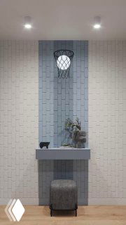 Акцентная вертикальная панель с синей вставкой, настенная полка с декором и небольшой пуф на фоне светло‑серой кирпичной отделки в интерьере квартиры.