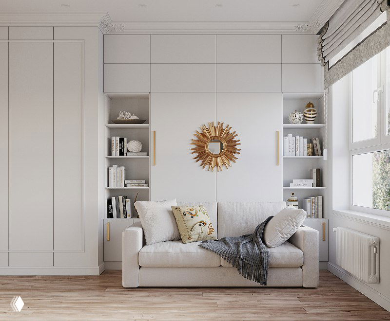 Светлый интерьер небольшой спальни‑гостиной: диван у встроенных книжных полок, декоративное зеркало‑«солнце», панельная стеновая система и большое окно.