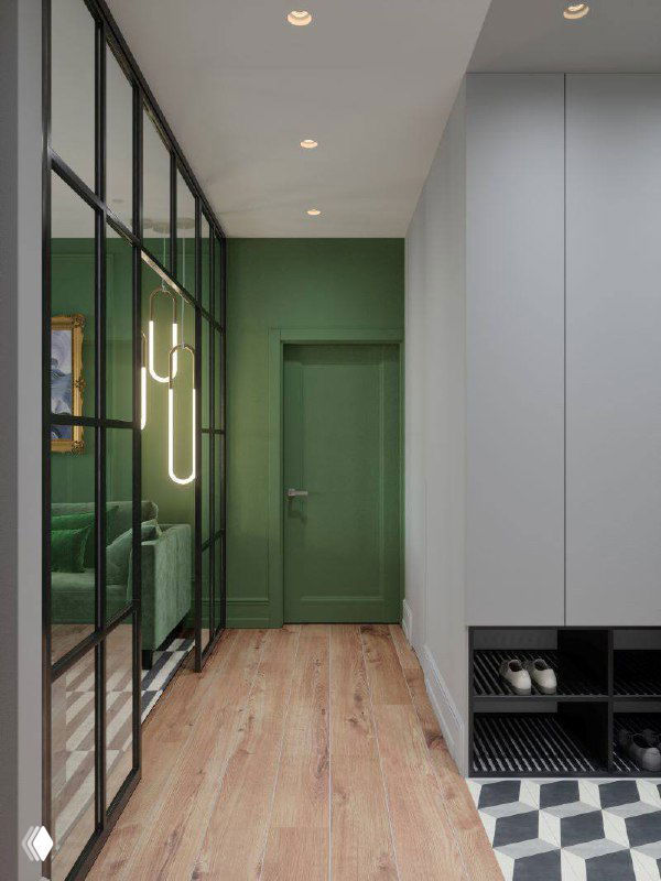 Длинная прихожая с деревянным полом, чёрной стеклянной перегородкой, встроенными обувницами и зелёной дверью в глубине.