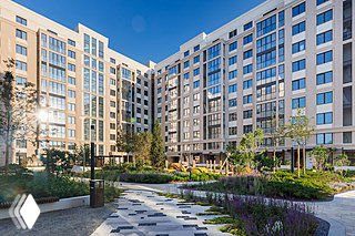 Вид во внутренний двор современного жилого комплекса «Александровский сад» с благоустроенной прогулочной зоной, дорожками, озеленением и многоэтажными фасадами.