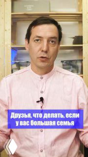 Кадр превью видео: мужчина в светлой рубашке на фоне стеллажей обращается к камере и рассказывает об объединении двух квартир для большой семьи.
